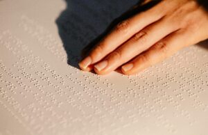 Hand feeling Braille text on paper, highlighting tactile reading for the visually impaired.